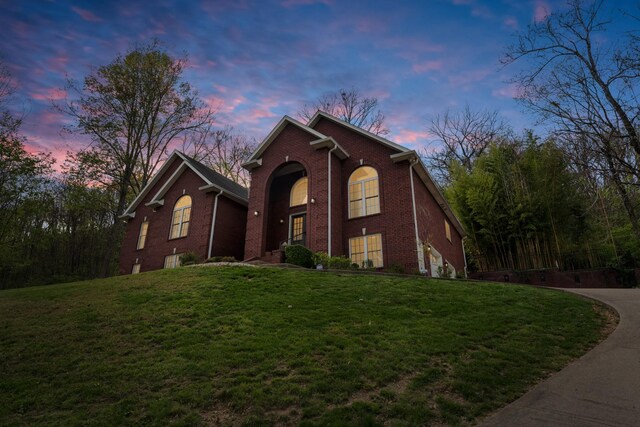 traditional-style home featuring a yard and brick siding