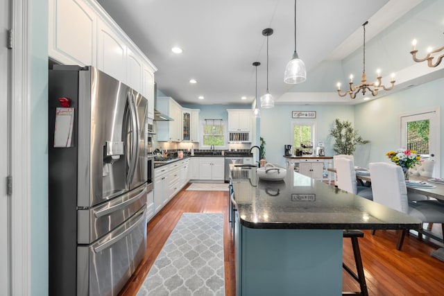 kitchen featuring white cabinetry, a breakfast bar, a healthy amount of sunlight, appliances with stainless steel finishes, and wood finished floors