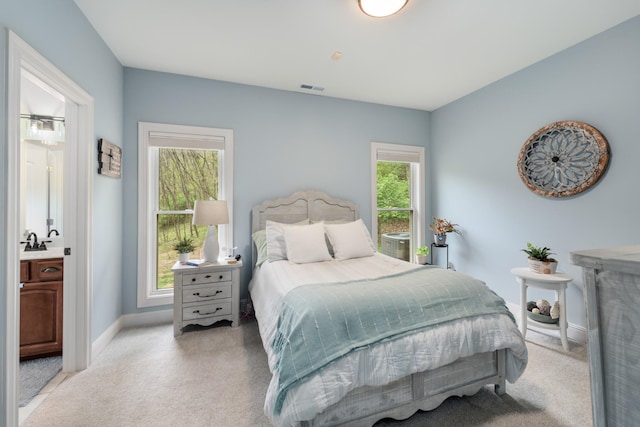 bedroom featuring a sink, visible vents, baseboards, and light colored carpet