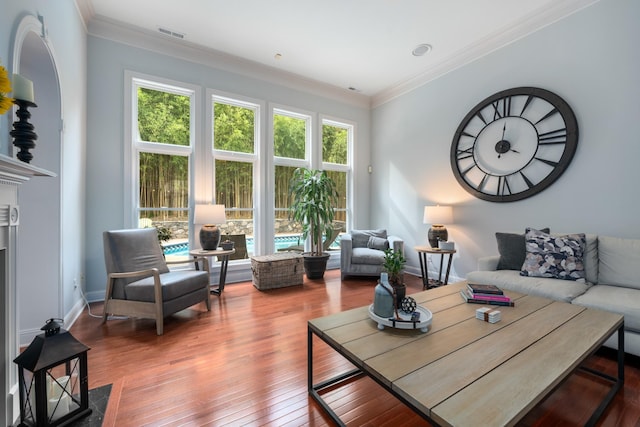 living room with crown molding, visible vents, baseboards, and wood finished floors
