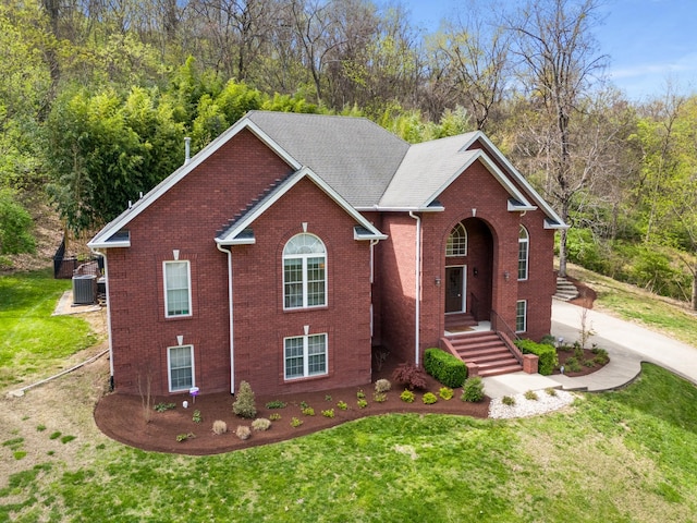 view of front of house featuring central AC unit, a front lawn, and brick siding