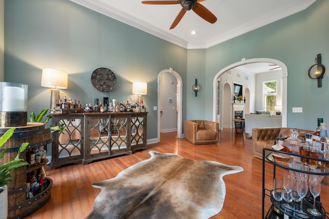 interior space with crown molding, wood-type flooring, ceiling fan, and arched walkways