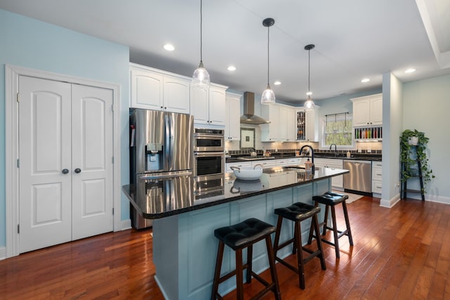 kitchen with dark wood-style floors, appliances with stainless steel finishes, wall chimney exhaust hood, and backsplash
