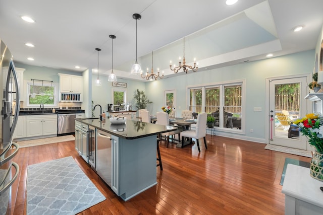 kitchen featuring white cabinets, plenty of natural light, an inviting chandelier, dark countertops, and appliances with stainless steel finishes