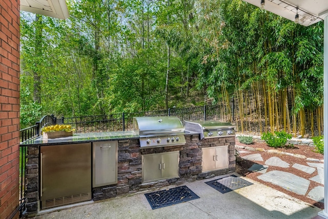 view of patio featuring fence, a wooded view, and area for grilling