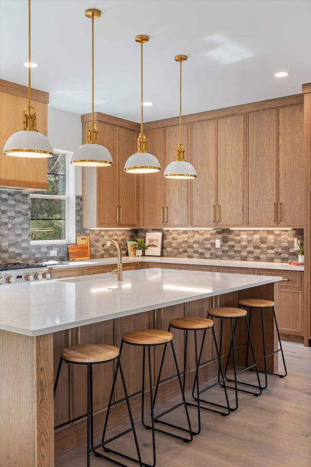 819 Davidson Dr, Nashville, TN 37205 - kitchen featuring light wood-type flooring, a breakfast bar, hanging light fixtures, a center island with sink, and backsplash