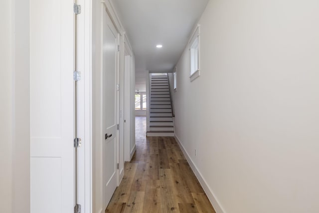 corridor featuring recessed lighting, stairway, light wood-type flooring, and baseboards