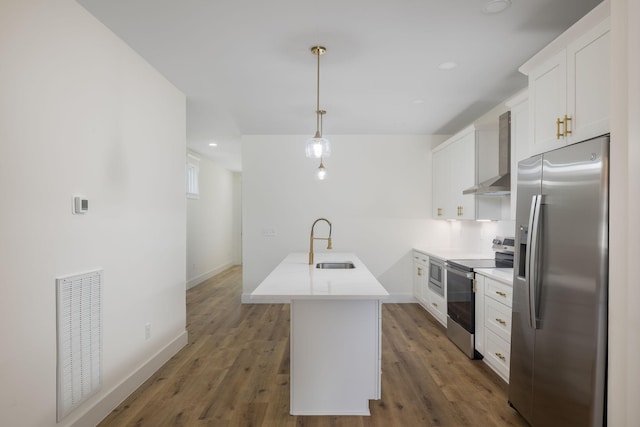 kitchen with wall chimney range hood, white cabinetry, visible vents, appliances with stainless steel finishes, and a sink