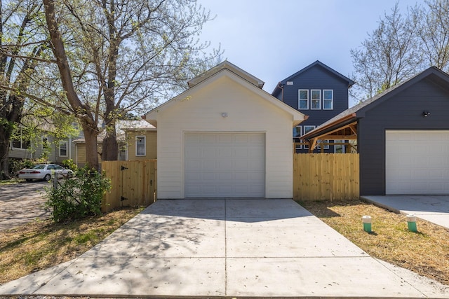 view of front of property with an outbuilding, a detached garage, fence, and concrete driveway