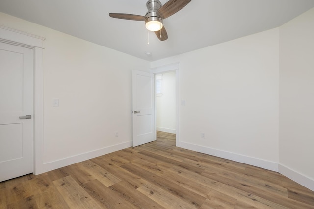 spare room featuring light wood-style flooring, ceiling fan, and baseboards