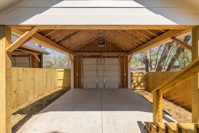 garage featuring concrete driveway, a garage door opener, and a detached garage