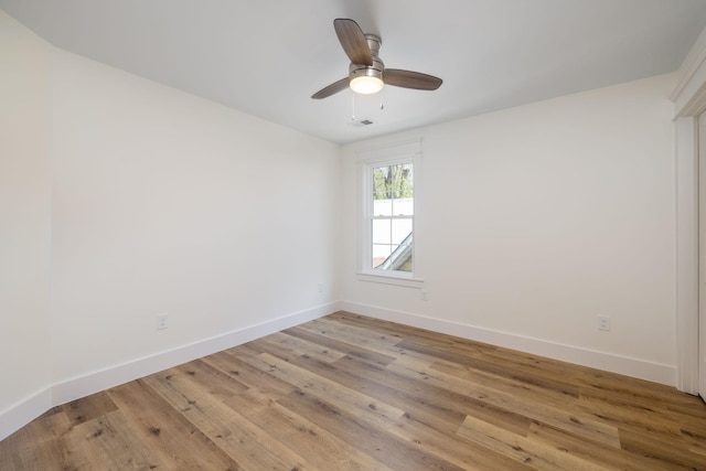 spare room featuring baseboards, light wood finished floors, and ceiling fan