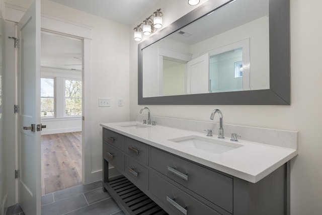 full bath featuring tile patterned floors, double vanity, a sink, and baseboards