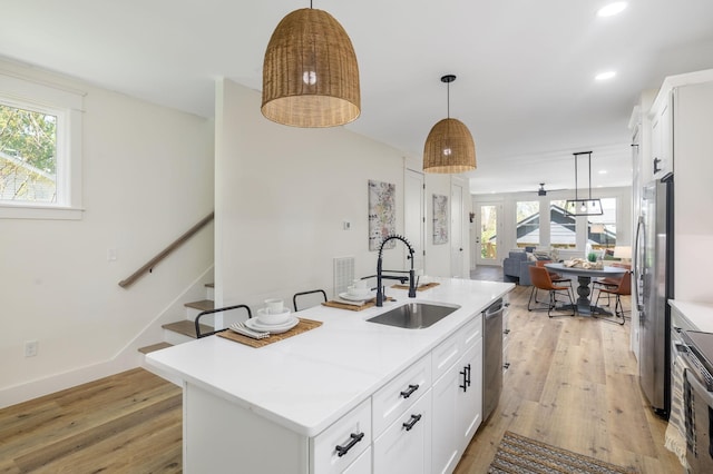 kitchen featuring plenty of natural light, light wood finished floors, a sink, and appliances with stainless steel finishes