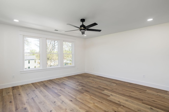 spare room with a ceiling fan, visible vents, recessed lighting, wood finished floors, and baseboards