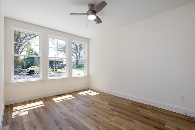 spare room with plenty of natural light, visible vents, baseboards, and wood finished floors