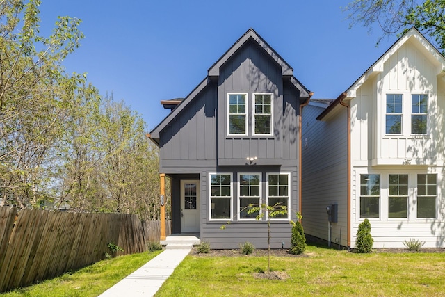 view of front of property featuring board and batten siding, a front lawn, and fence