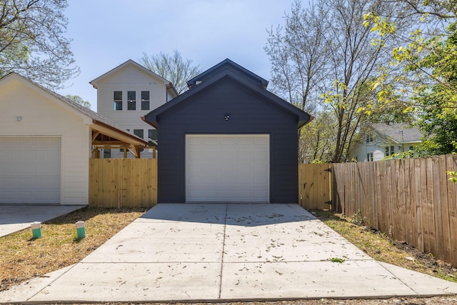 view of front of house featuring an outbuilding, concrete driveway, and fence
