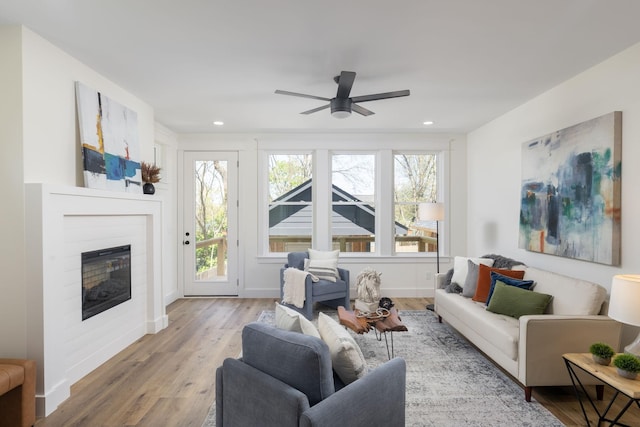 living room featuring baseboards, a ceiling fan, recessed lighting, wood finished floors, and a glass covered fireplace