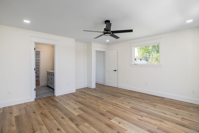 unfurnished bedroom featuring baseboards, recessed lighting, ensuite bath, and light wood-style floors