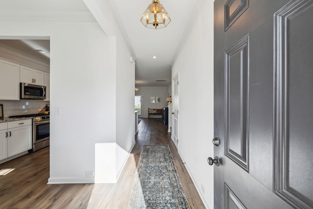 hallway featuring baseboards, ornamental molding, a chandelier, recessed lighting, and dark wood-style floors