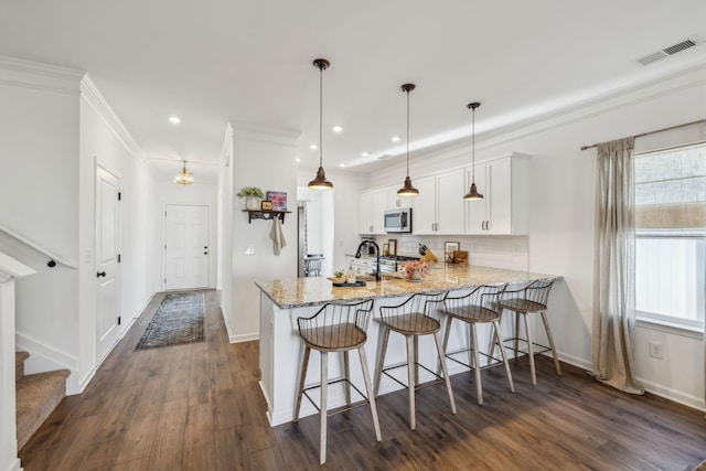 kitchen with baseboards, a peninsula, visible vents, dark wood finished floors, and appliances with stainless steel finishes