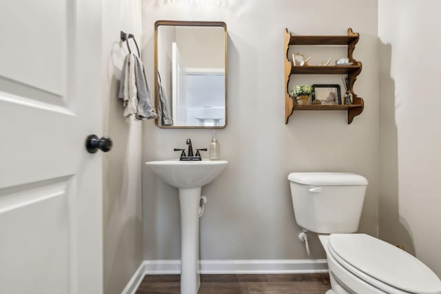 half bath featuring toilet, wood finished floors, and baseboards