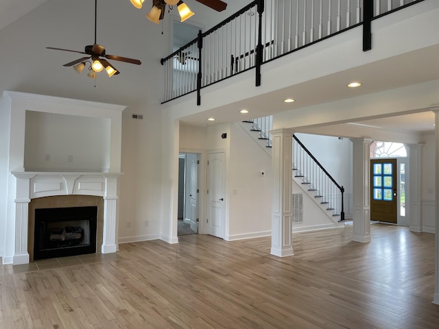 265 Gray Hawk Trl, Clarksville, TN 37043 - unfurnished living room featuring ceiling fan, stairway, baseboards, light wood finished floors, and ornate columns