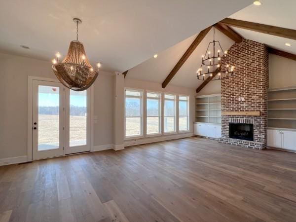 unfurnished living room featuring baseboards, an inviting chandelier, a fireplace, beamed ceiling, and wood finished floors