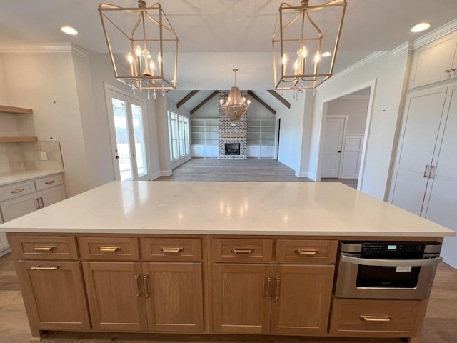 kitchen featuring open floor plan, a brick fireplace, an inviting chandelier, and stainless steel oven
