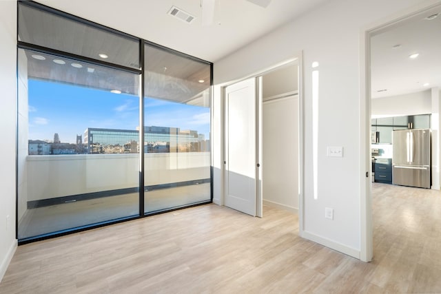 unfurnished bedroom with visible vents, baseboards, freestanding refrigerator, and wood finished floors
