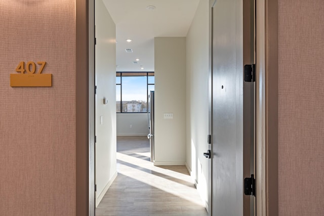 corridor featuring wood finished floors, baseboards, and recessed lighting