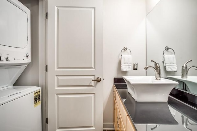 clothes washing area with stacked washer and dryer, laundry area, and a sink