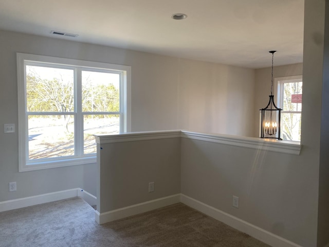 unfurnished room featuring a chandelier, baseboards, visible vents, and carpet floors