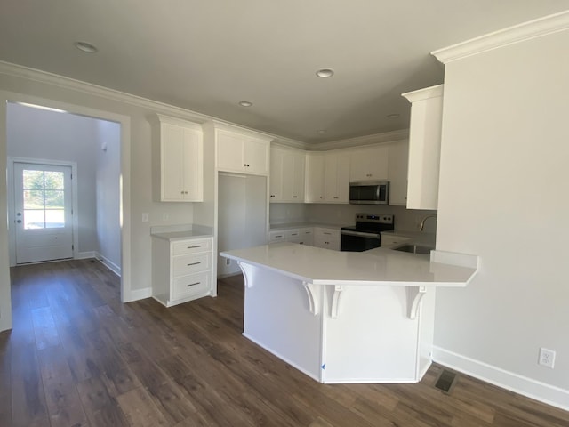 kitchen featuring baseboards, a peninsula, crown molding, appliances with stainless steel finishes, and a sink