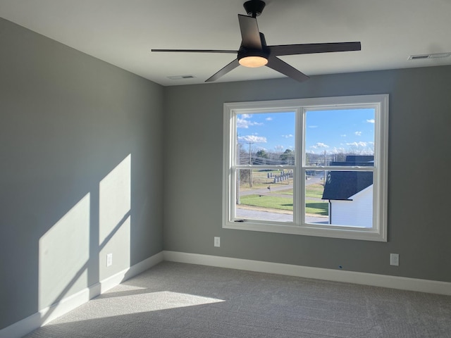 unfurnished room with visible vents, baseboards, a ceiling fan, and light colored carpet