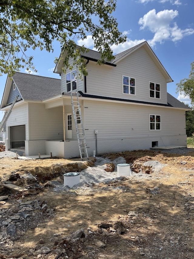 exterior space featuring an attached garage and a shingled roof
