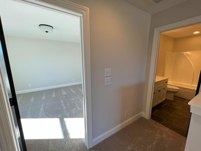 hall featuring dark carpet, baseboards, and visible vents