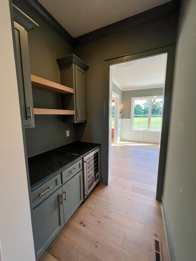 kitchen with light wood-style floors, ornamental molding, visible vents, beverage cooler, and gray cabinetry