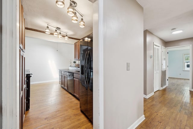 corridor featuring light wood-style floors and baseboards