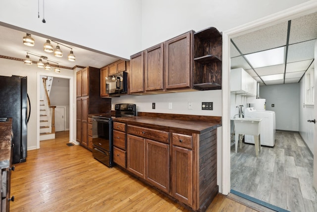 kitchen with light wood-style flooring, butcher block countertops, washer / clothes dryer, open shelves, and black appliances