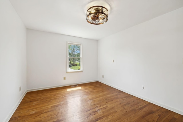empty room with baseboards, wood finished floors, and visible vents
