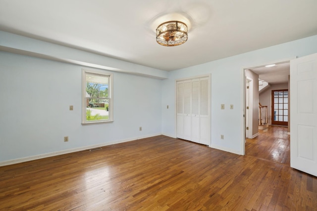 unfurnished bedroom featuring hardwood / wood-style flooring, multiple windows, and visible vents