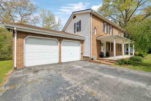 view of front facade with brick siding, an attached garage, driveway, and covered porch