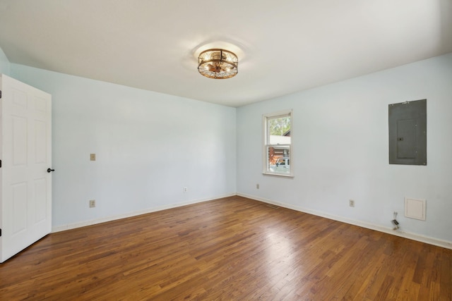 spare room featuring baseboards, wood finished floors, and electric panel