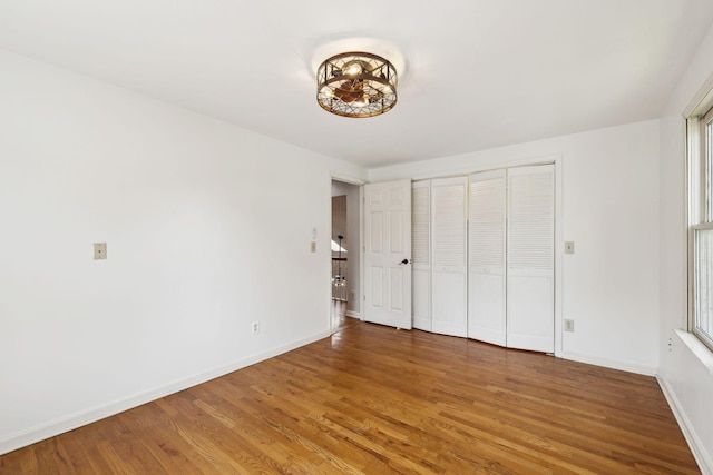 unfurnished bedroom featuring light wood-style flooring, a closet, and baseboards