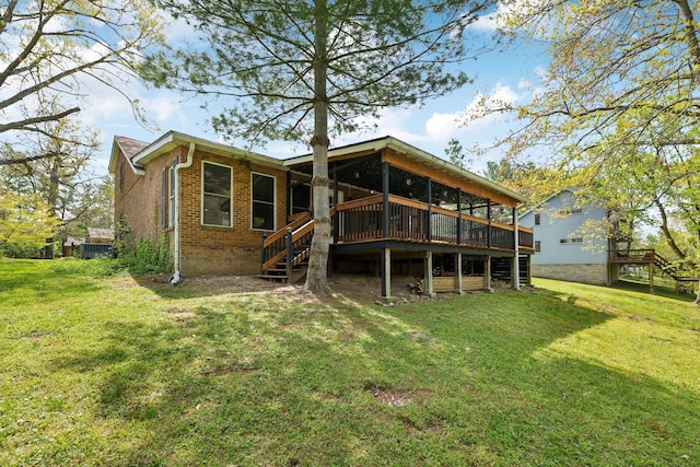 back of property featuring brick siding, a yard, stairway, and a deck