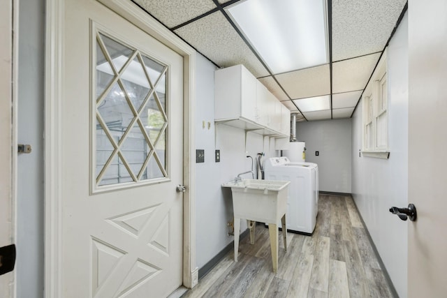washroom with baseboards, light wood-style floors, washer / clothes dryer, and cabinet space