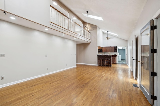 unfurnished living room with light wood-type flooring, baseboards, visible vents, recessed lighting, and high vaulted ceiling