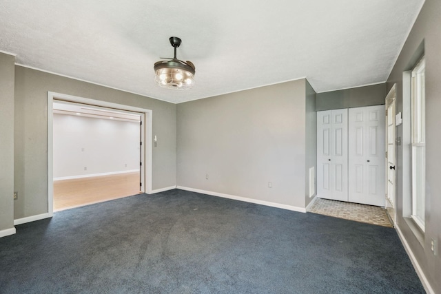 unfurnished bedroom with dark colored carpet and baseboards